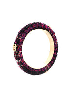 A close-up image of a circular bracelet with a textured exterior. The bracelet features a pattern of deep purple and black, giving it a rich, velvety appearance. The interior of the bracelet is smooth and wooden, contrasting with the plush exterior. 