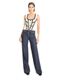 Woman wearing a black and white patterned top with high-waisted blue jeans on a white background