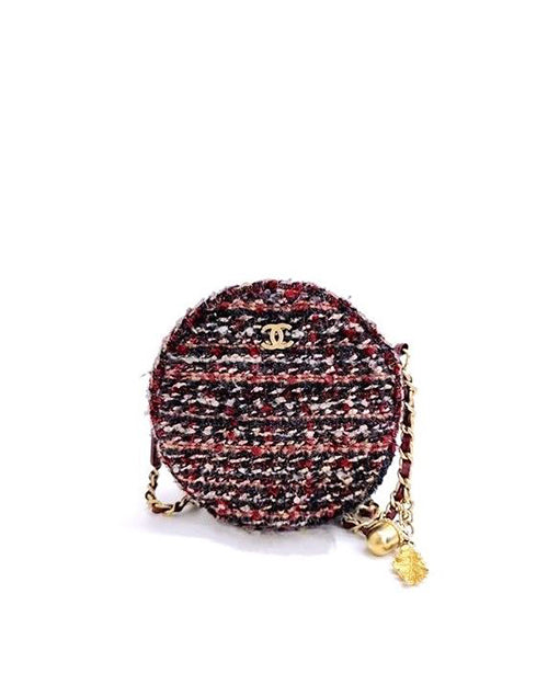 A round, tweed fabric shoulder bag with a blend of red, black, white and additional color threads. The bag features a gold-tone metal chain strap with interwoven fabric and a matching gold-tone metal logo on the front. A tassel charm hangs from the strap, adding an elegant detail to the design.