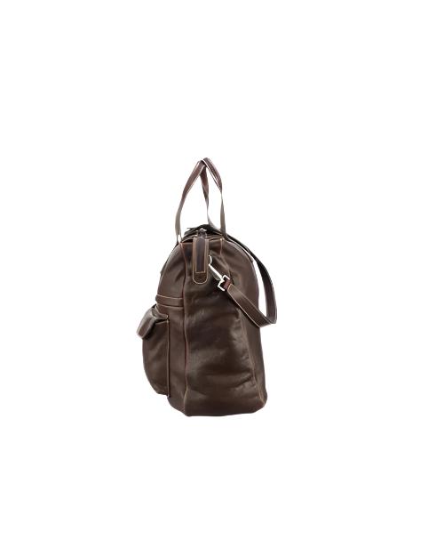 The side of a brown leather satchel travel bag with a shoulder strap, handles and front pockets.