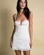 A person is wearing a white, crocheted dress with thin straps. The bodice is fitted and showcases a delicate, tight-knit crochet pattern, while the cut-out detail just below the bust is bordered by a slightly thicker, more open crochet weave, creating a subtle contrast. The skirt portion of the dress continues with a mix of tight and loose crochet patterns. The dress extends to knee length.