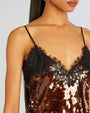 Close up of a a person's top wearing a spaghetti strap, brown sequined top with black lace trim.