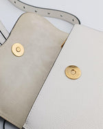 White leather beltbag with gold snap fasteners, showcasing soft felt interior and stitching details. Includes an open flap and belt accessory.