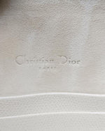 Inside a bag with felt-like material with a small leather stitched pocket that is peaking under a 'Christian Dior' engraving.