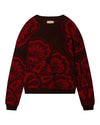 Dark-colored sweater featuring a bold red floral pattern with large flowers covering most of the surface, and a small label at the back of the neck.