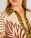 Close up of button up shirt featuring polka dot and palm leaf design in shades of pink, white, and green.