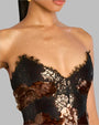 A close up of a person showing the top part of the body, wearing a strapless dark brown sequin dress with black lace.