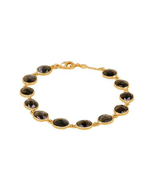 A gold bracelet featuring a series of oval-shaped, dark-colored gemstones set in individual gold bezels. The bracelet has a clasp closure and the gemstones are evenly spaced around the entire length of the bracelet.