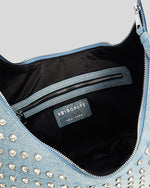 A close-up view of a bag with a black interior and a silver zipper. The exterior of the garment is adorned with numerous small, shiny silver studs creating a sparkling effect.