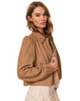Person wearing a light brown suede jacket over a white lace dress.