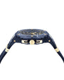 ide view of a luxury wristwatch with a dark blue strap and case, accented with gold details. The crown, which has a blue center, and gold screws enhance the design. The partially visible watch face features gold hour markers and hands.