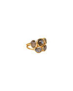A close-up image of a gold ring featuring five labradorite gemstones, positioned at an angle to show both the front and side views. The stones include three teardrop-shaped and two oval-shaped labradorites, set in gold bezels with a double band design.