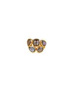 A gold ring featuring five irregularly shaped gemstones with dark, reflective surfaces. The stones are set in gold bezels, creating a bold and unique design.