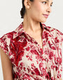 A close up of the top of a woman wearing a red floral blouse on a white background