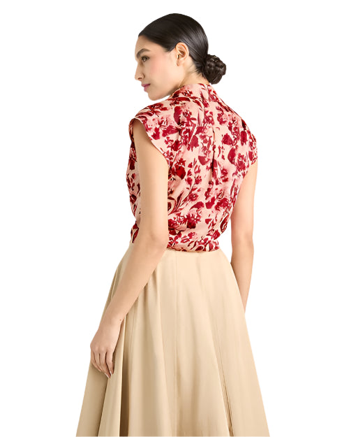 Back view of a person in a red and white floral sleeveless top and beige skirt, against a light background.