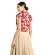 Back view of a person in a red and white floral sleeveless top and beige skirt, against a light background.