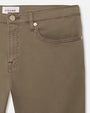 The image shows a close-up of the upper part of a pair of sage colored trousers. Visible are the waistband with a button, belt loops, and the pocket lining. The brand ‘FRAME’ is visible on a tag at the top. These trousers appear to be well-constructed and stylish.