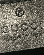 Closeup of leather Gucci tag with "Gucci made in Italy" embossed on leather bag.