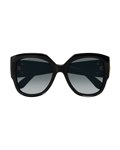 Front view of black, oversized cat-eye sunglasses with grey-tinted lenses and a thick frame. 