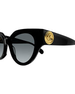 Close-up of black narrow cat-eye sunglasses with dark grey lenses and  a gold circular logo on the temples.