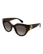 Tortoiseshell colored, narrow cat-eye sunglasses with brown lenses and  a gold circular logo on the temples.