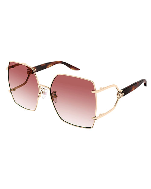 Rectangular oversized Gucci sunglasses. The temples are tortoise color, and the large lenses appear to be a gradient red with GG logo and gold rim. The brand name ‘Gucci’ is visible on the top corner of the right lens.