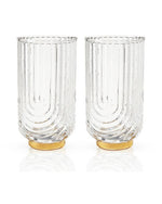 Two tall, clear glass tumblers with textured, vertical grooves. They have a curved design and golden bases, conveying elegance and sophistication.