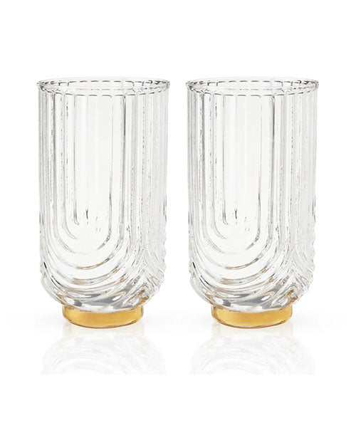 Two tall, clear glass tumblers with textured, vertical grooves. They have a curved design and golden bases, conveying elegance and sophistication.