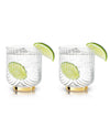 Two elegant glasses with striped details, each filled with a clear beverage and garnished with a lime wedge. Reflective gold bases add a touch of luxury.