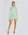 A model wearing a mint green lace dress and a high neckline. The mini dress with a sheer material all throughout and two cut outs at the collar bone. The dress is styled with silver accessories.