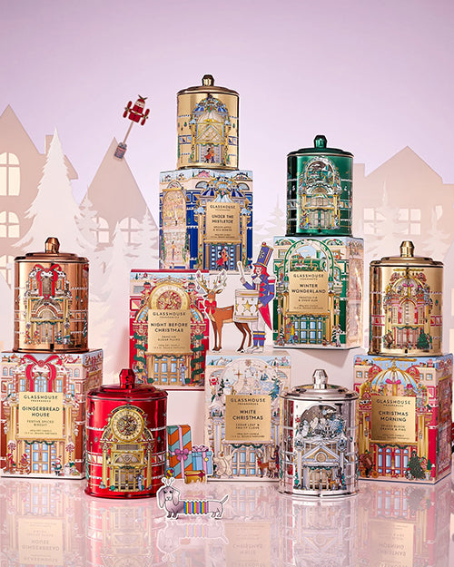 Collection of decorative holiday candles with matching festive boxes featuring seasonal holiday designs.