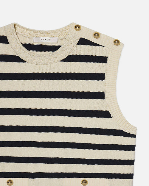 A sleeveless knitted top with horizontal black- and cream-colored stripes. The top has a round neckline with braided detailing and features gold buttons on the left shoulder. The brand label "FRAME" is visible at the back of the neckline.