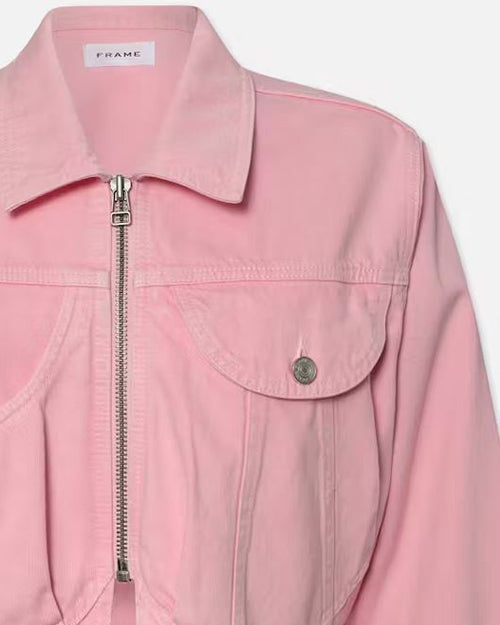 Close-up of pink denim jacket with silver zipper and button. Features classic collar, two heart-shaped chest pockets, and long sleeves. Cropped style ending at waistline. Label 'FRAME' visible on inside collar.