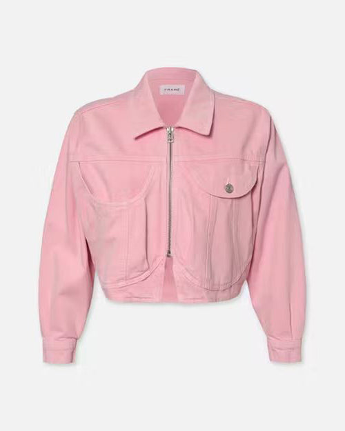 A pink denim jacket with a silver zipper and button displayed against a white background. The jacket has a classic collar, two chest pockets with flap on left side, and long sleeves. It appears to be a cropped style, ending around the waistline. The brand label ‘FRAME’ is visible on the inside collar area, suggesting it is from the FRAME clothing line.