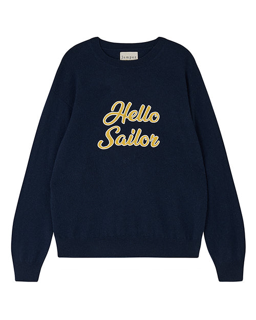 A navy-blue sweater with long sleeves and a round neckline. The sweater has the phrase "Hello Sailor" written in yellow cursive letters on the front. The brand label "Jumper" is visible at the back of the neckline.