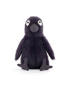 Plush toy bird with dark purple fur, large white and black eyes, a textured beak, and contrasting material feet, sitting upright with legs stretched forward.