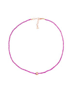 A delicate pink beaded necklace with a rose gold clasp and adjustable chain, featuring a small rose gold accent at the center. The design is simple and elegant.