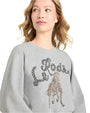 Woman wearing a gray sweatshirt with decorative text and horse design on a plain background