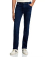 Person standing upright wearing dark blue jeans and white sneakers with black accents, with one hand in the pocket.