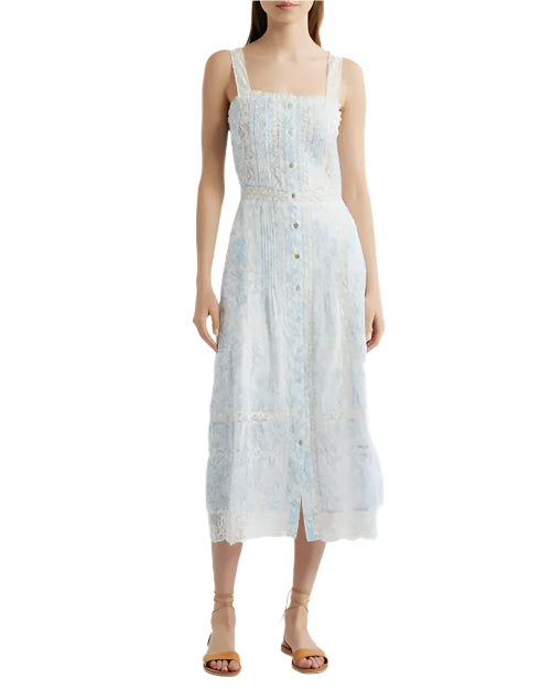 A person wearing a light blue and white dress with buttoning down the front and over the shoulder straps. The dress has lace detailing and a fitted bodice that flares out into an A-line skirt. The person is also wearing tan strappy sandals.