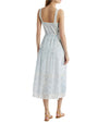 The backside view of a person wearing a light blue and white dress with a half open back and over the shoulder straps. The dress has lace detailing and a fitted bodice that flares out into an A-line skirt. The person is also wearing tan strappy sandals.