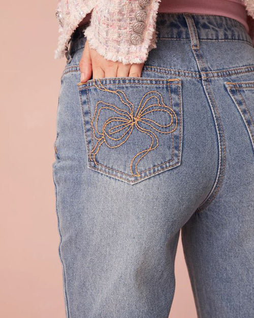 A close-up on the left pocket on jeans with a brown bow stitching.