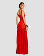 A backside view of a brunette model with her hair tied up wearing a long, sleeveless red dress with a scoop neck, fitted bodice and a gathered skirt. The model is wearing multiple bangles on both wrists and dangly red earrings.