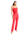 Person in a red silk camisole and matching high-waisted pants, wearing nude high-heeled sandals, standing against a white background