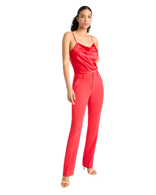 Person in a red silk camisole and matching high-waisted pants, wearing nude high-heeled sandals, standing against a white background