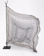 Gray scarf with white skull pattern on a stand against a white background