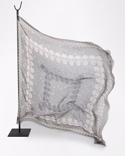 Gray scarf with white skull pattern on a stand against a white background