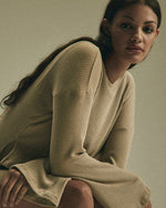 A person wearing a taupe long sleeve sweater .