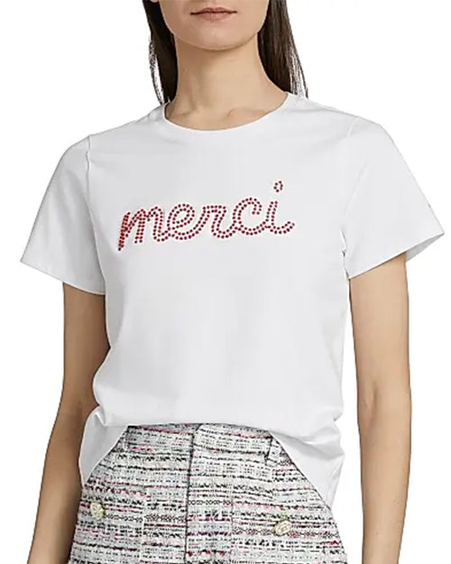 White t-shirt with 'merci' text in red rhinestones worn by a person.