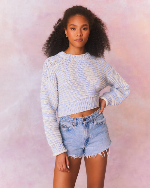 Blue and cream cropped pullover sweater with textured knit and crew neckline. Long cuffed sleeves and ribbed hem above waistline.